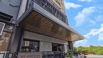 Un hotel con fachada moderna, una entrada destacada y cielo despejado al fondo.