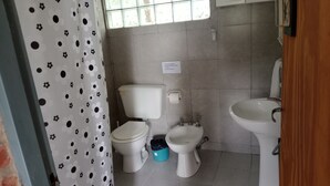 A bathroom with two toilets, a sink, and a trash bin. - Cabañas Refugio LAS ACEQUIAS (Tanti)