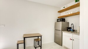 A kitchen with a stainless steel refrigerator, a microwave, a sink, and a wooden table with two chairs. - #8 | South Padre Studio | Pool | Walk 2 Beach (South Padre Island)