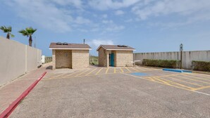 A parking lot with marked spaces, a building with a door, and a sign indicating a disabled parking spot. - #8 | South Padre Studio | Pool | Walk 2 Beach (South Padre Island)