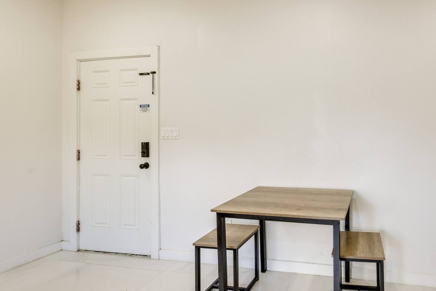 Una habitación con una puerta blanca, una mesita y dos mesitas auxiliares a juego.