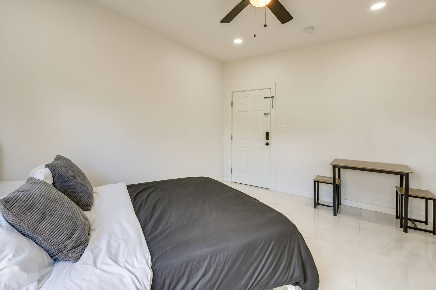 Quarto com cama, escrivaninha e porta.