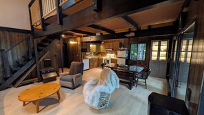 Interior rústico de uma cabana com sala de jantar, cozinha e escada.