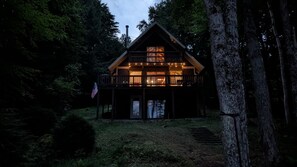 A cabin with a balcony, a door, and an American flag.