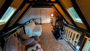 An attic bedroom with a sloped ceiling, a bed, a chair, a small table, and a window.