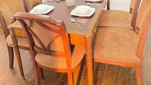 Une table à manger dressée avec des assiettes, des couverts et un vase rempli de fleurs jaunes.