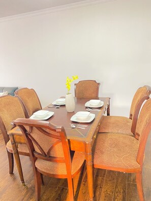 Een eettafel gedekt met borden, bestek en een vaas met gele bloemen.