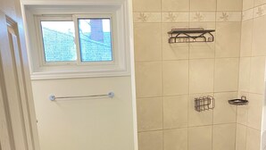 Une salle de bain avec une baignoire, une fenêtre et des murs carrelés.