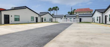 A row of modern, single-story buildings with a paved walkway in between.