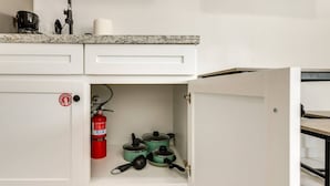 A kitchen with a white cabinet, a fire extinguisher, and green pots. - #9 | Beach Escape Studio w/Pool | Walk Everywhere (South Padre Island)