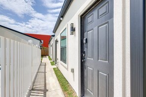 A narrow pathway leading to a building with a grey door and a red roof. - #9 | Beach Escape Studio w/Pool | Walk Everywhere (South Padre Island)