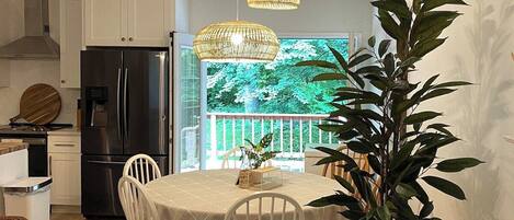 A compact kitchen with white cabinets, a black refrigerator, and a dining area with a round table and chairs.