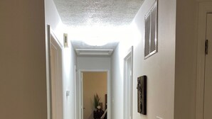 Un couloir étroit avec un plancher en bois, des murs blancs et une lucarne.