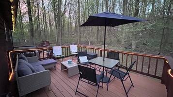 A deck with outdoor furniture, including a sofa, chairs, and a table, surrounded by a railing.