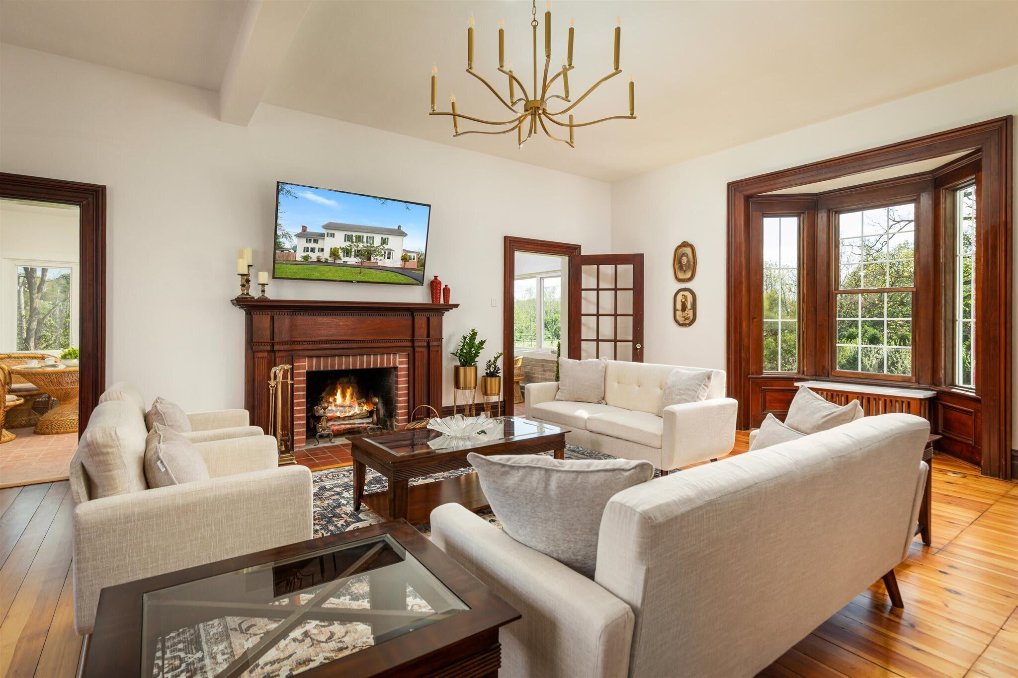 A living room with a fireplace, a television mounted above it, and a large window providing a view of the outdoors.