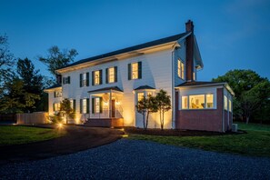 A two-story house with a front porch, a garage, and a well-maintained lawn. - Shenandoah Heritage | Restored 1870 Home w/ Sauna, Hot Tub + Chef's Kitchen (Front Royal)