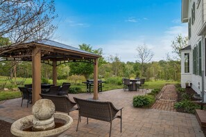 Eine Terrasse mit Gartenmöbeln, einer Pergola und einem Feuerkorb.