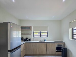 Eine moderne Küche mit einem Edelstahl-Kühlschrank, einem Einbauofen, einer Spüle und einem Fenster mit Blick.