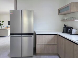 Eine moderne Küche mit einem Edelstahlkühlschrank, Holzschränken und einer weißen Arbeitsplatte.