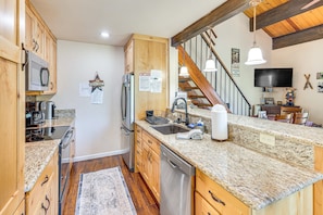 A kitchen with wooden cabinets, a stainless steel refrigerator, granite countertops, a built-in dishwasher, and a wooden floor. - 3-bedroom condo in fabulous Kings Beach close to Beach and Ski Resorts. (Kings Beach)