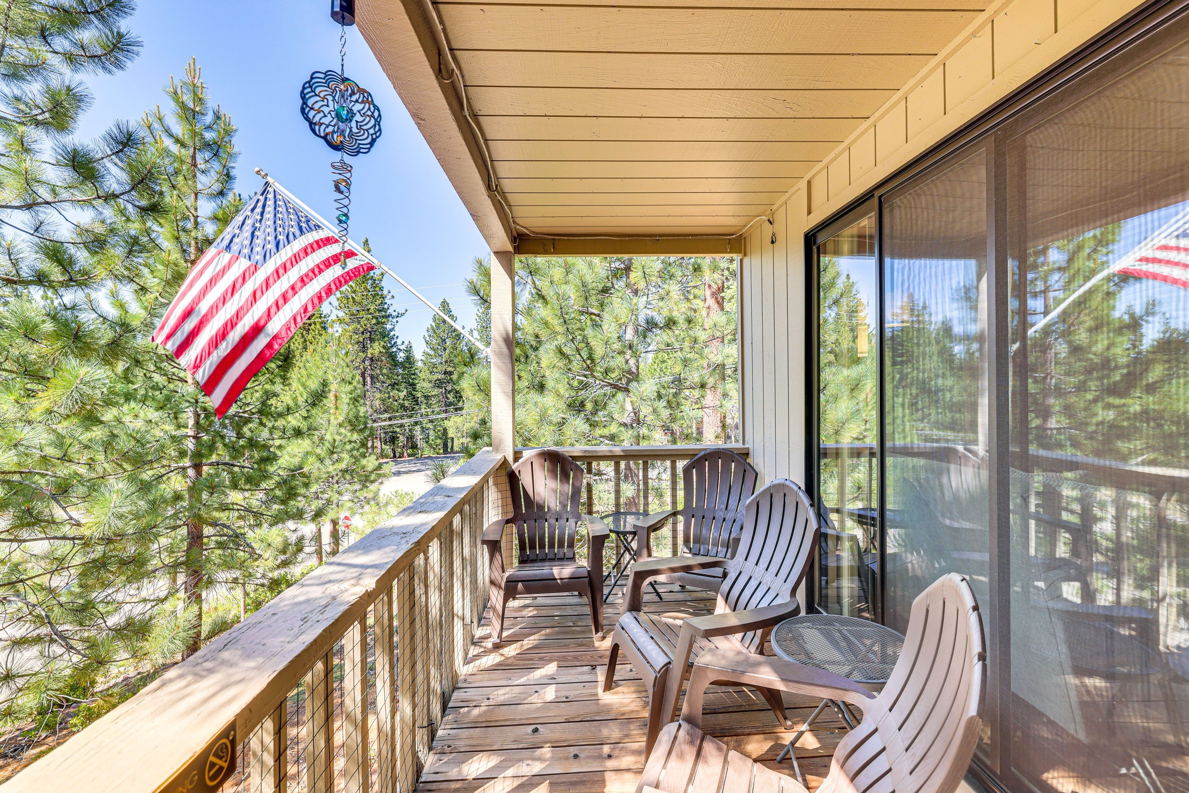 A wooden deck with outdoor seating and a view of pine trees.