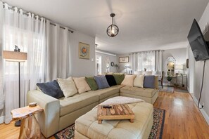 A living room with a sofa, ottoman, and a wooden coffee table. - The Nest - Main House (Lead)