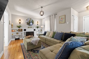 A living room with a fireplace, a sofa set, and a patterned rug. - The Nest - Main House (Lead)