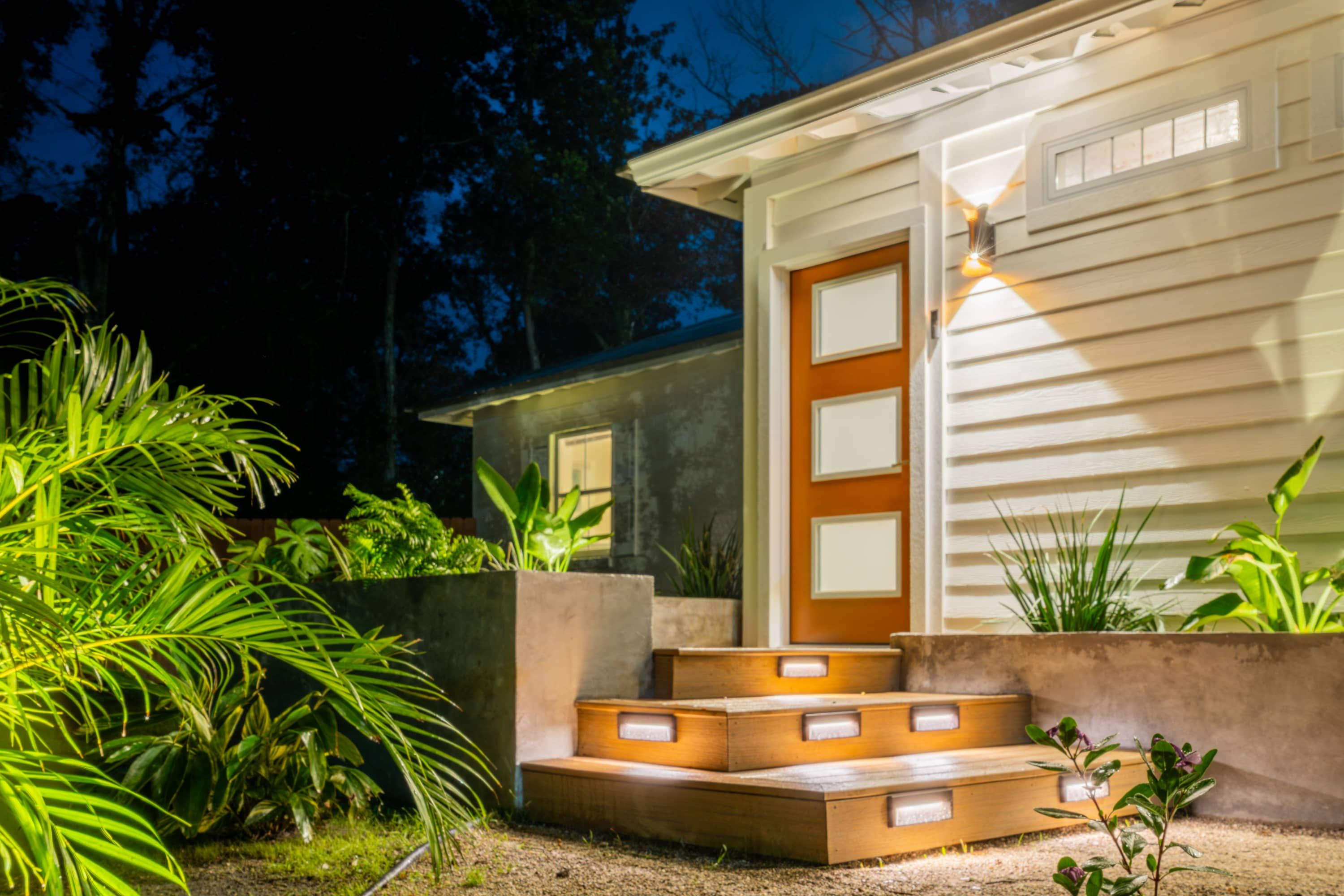 A modern house with a wooden door and steps leading to the entrance.
