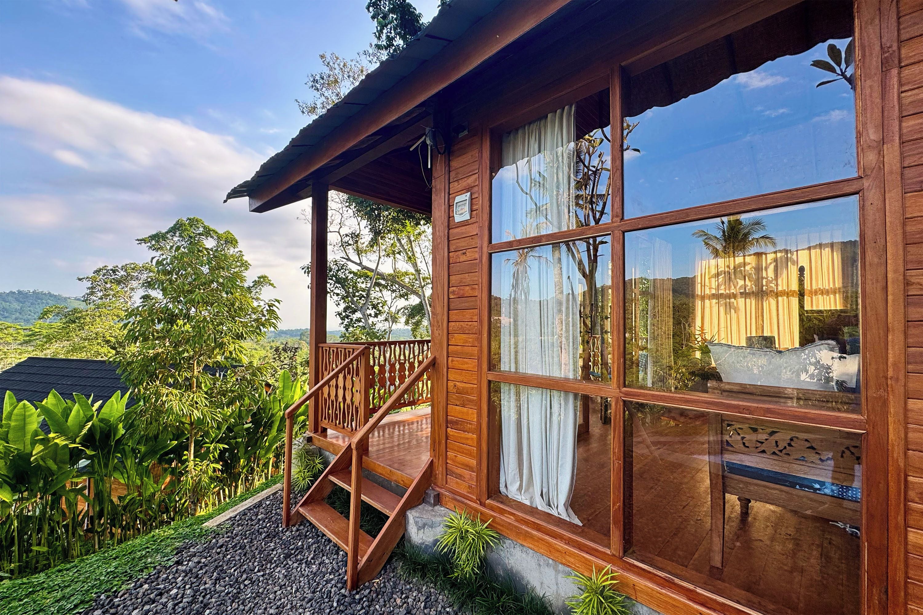 Una cabaña de madera con balcón, ventanas amplias y vistas de la vegetación circundante.
