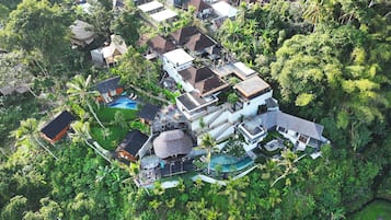 Vista aérea de una zona residencial con varias casas, una piscina y abundante vegetación.