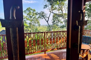 A wooden balcony with a view of a lush landscape.