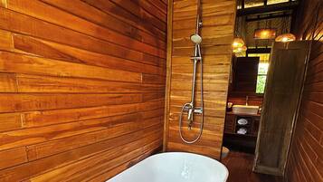 Un interior de madera con una bañera, ducha y lavamanos.