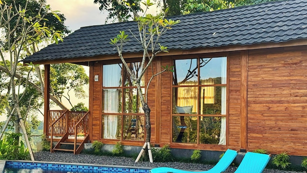 A wooden house with a swimming pool and lounge chairs. - Aura Cemapaka (Karangasem)