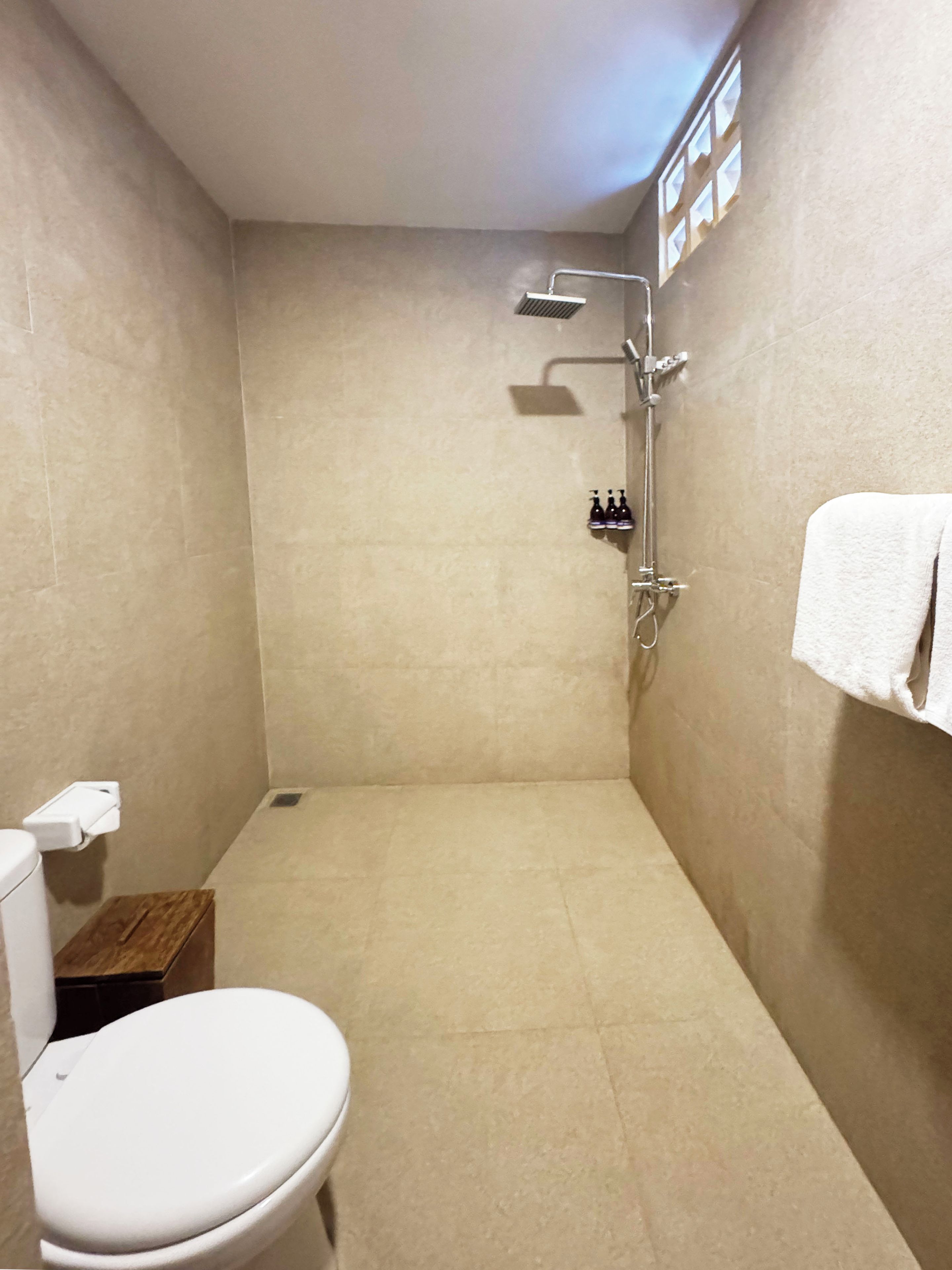 Un baño pequeño con azulejos, un inodoro, una ducha y un perchero para toallas.