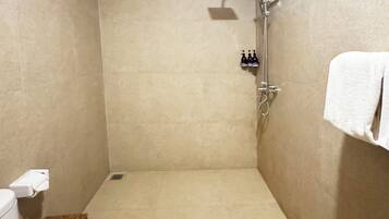 Un baño pequeño con azulejos, un inodoro, una ducha y un perchero para toallas.