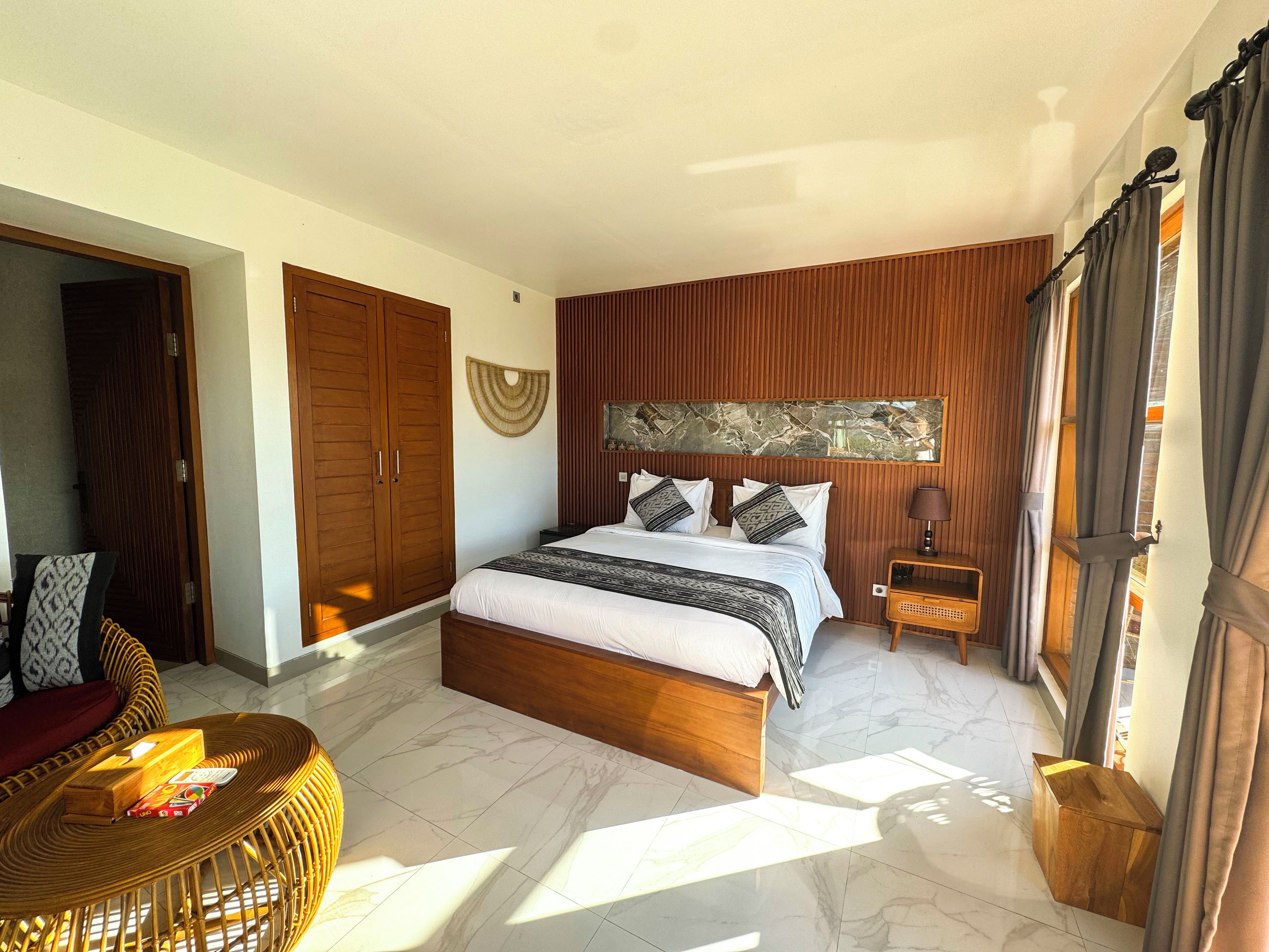 Quarto com cama, guarda-roupa de madeira e cadeira de vime.