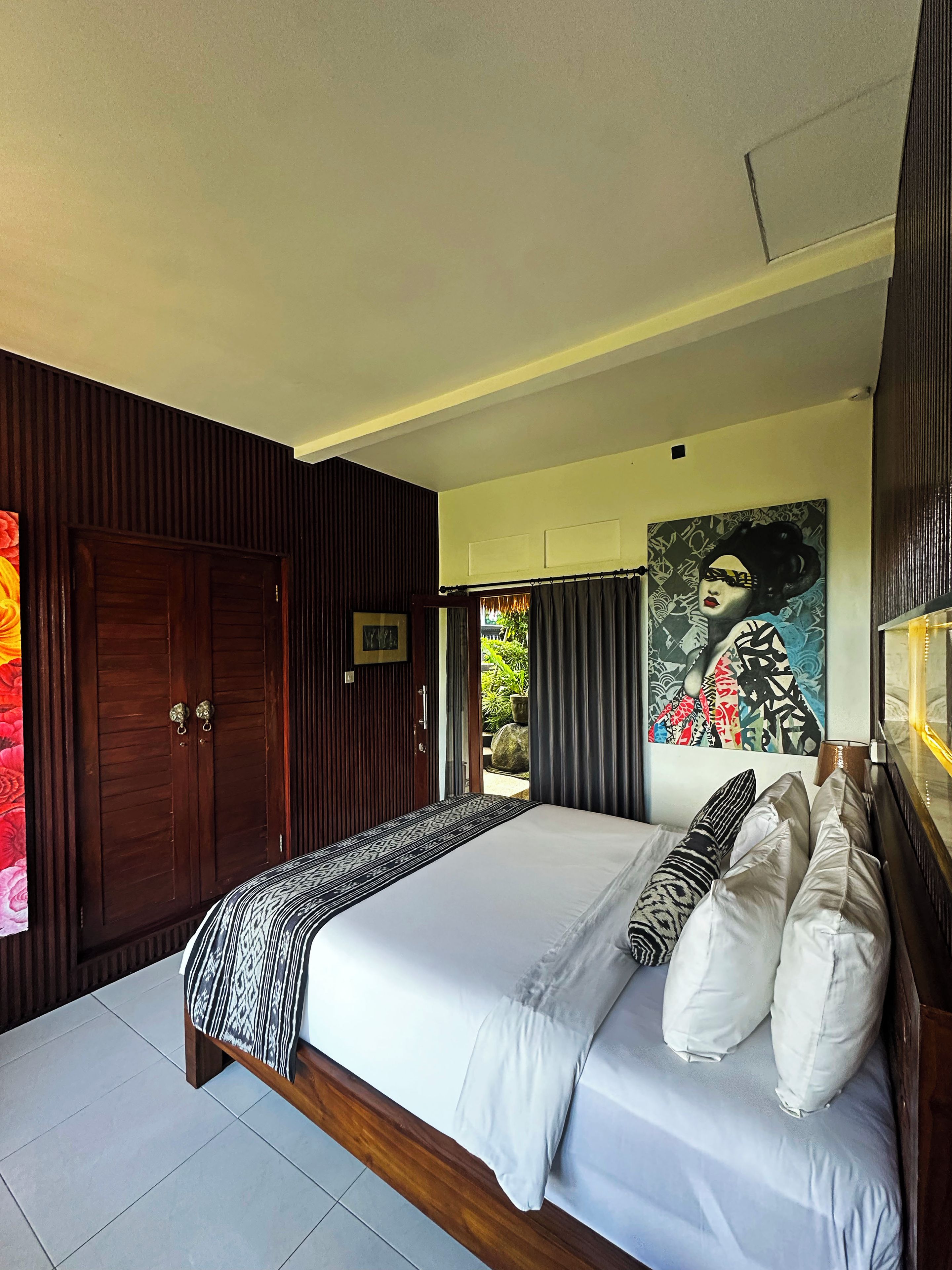 Quarto com uma cama grande, um guarda-roupa de madeira e um quadro na parede.