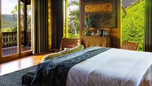 A bedroom with a large bed, a view of greenery, and a balcony. - Aura Cempaka (Sidemen)