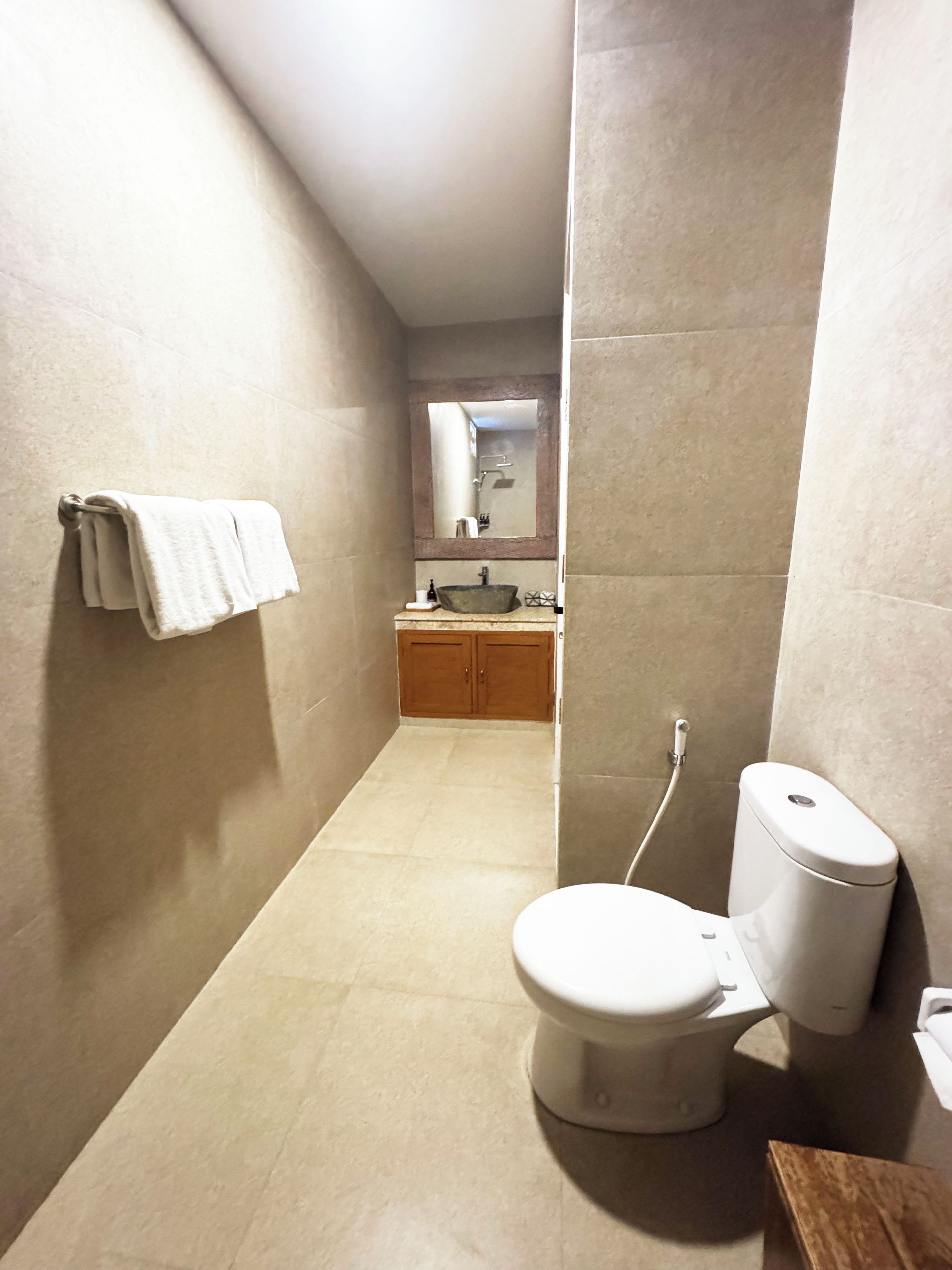 Un baño estrecho con un inodoro, un lavabo y un espejo.