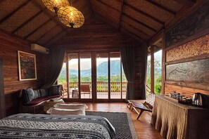 A wooden room with a bed, a table, and a view of the outdoors. - Aura Cempaka (Sidemen)