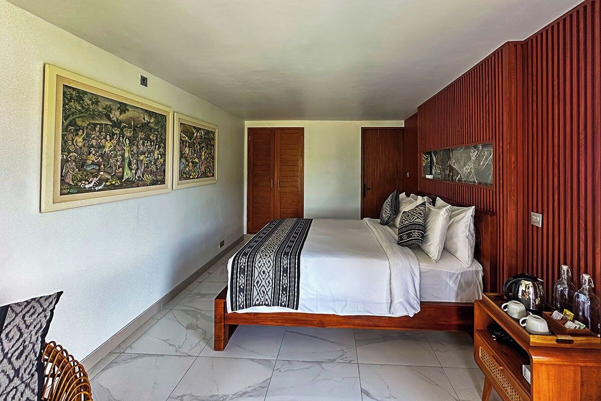 A bedroom with a bed, wooden wardrobe, and artwork on the walls.