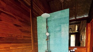 A bathroom with a large bathtub, a shower, and patterned tiles. - Aura Cemapaka (Karangasem)