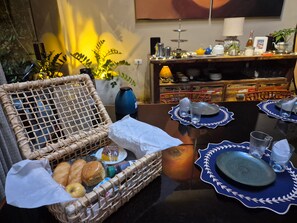 Una mesa de comedor dispuesta con platos, vasos y una cesta de pan.