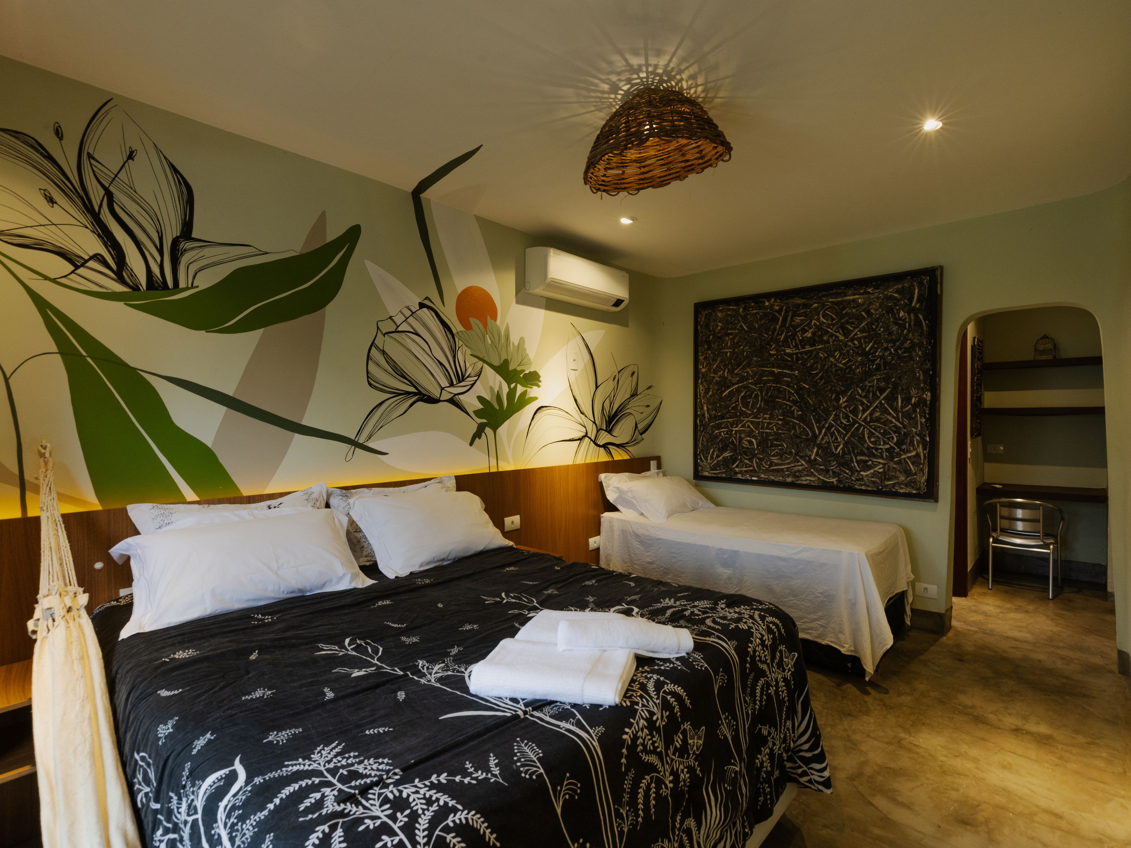 Habitación de hotel con dos camas, un mural floral grande, un cuadro abstracto moderno y una lámpara colgante.