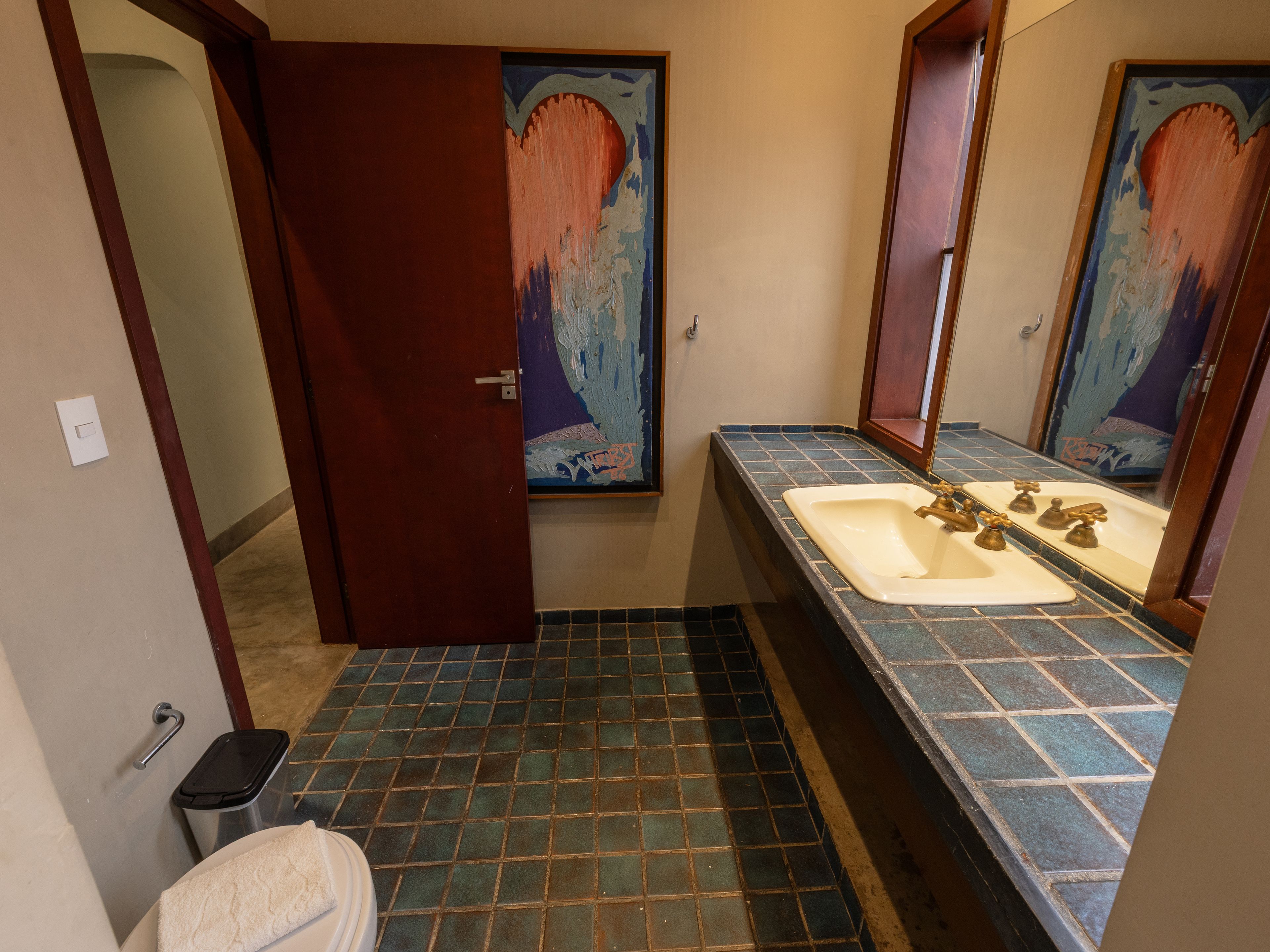 Een badkamer met een betegelde vloer, een wastafel met spiegel en een handdoek op de vloer.