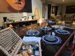 Een eetgedeelte met een tafel voor vier personen, omringd door rieten stoelen en een rieten bank.