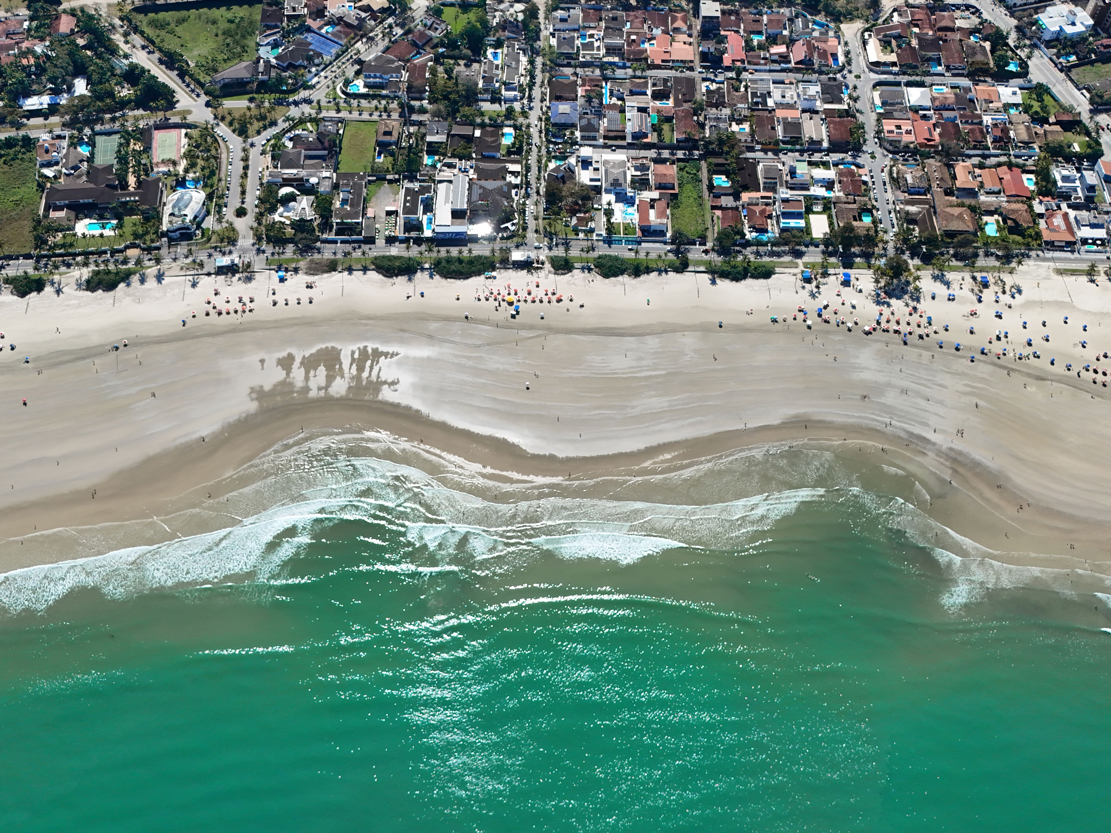 Vista aérea de una zona costera con playa, edificios residenciales y una carretera.