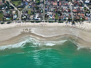 Une vue aérienne d’une zone côtière comprenant une plage, des immeubles résidentiels et une route.