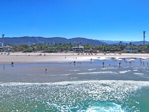 Ein Strand mit Menschen, Palmen und Bergen im Hintergrund.