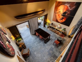 A spacious dining area with a high ceiling, a large table, and a view of the outdoor patio.